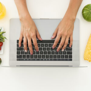 Laptop otoczony warzywami i owocami — konsultacja dietetyczna online